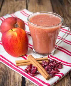 an apple and cinnamon drink on a napkin next to two apples