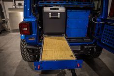 the back end of a blue truck with a wooden floor