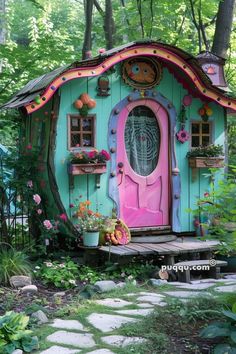 a small house with a pink door and windows in the woods, surrounded by flowers