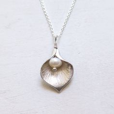 Silver Calla Lily Necklace - Gift for Her Classic and elegant gift for mother, friend or for bridesmaids. Dainty, easy to wear everyday or on special occasions. FEATURES: * A small freshwater pearl is wire wrapped with bright calla lily petal to form a flower pendant. * The petal is rhodium plated over brass. * Comes with sterling silver chain, finished with spring clasp closure. All sterling silver calla lily necklace: https://www.etsy.com/listing/476943360/ MEASUREMENTS: * the pendant is about Elegant Flower Pendant Jewelry Gift For Mom, Elegant Flower Pendant Jewelry For Mom, Silver Birth Flower Necklace For Wedding, Elegant Flower Pendant Necklace For Bridesmaid Gift, Elegant Birth Flower Jewelry For Anniversary, Delicate Silver Jewelry Gift For Mom, Delicate Sterling Silver Necklace For Bridesmaid, Delicate Silver Jewelry For Mom, Elegant Flower Pendant Jewelry For Bridesmaid Gift