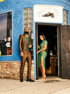 a man and woman standing in front of a blue building