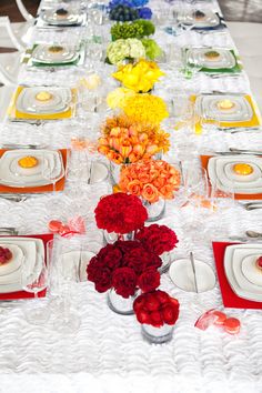 a long table is set with flowers and plates