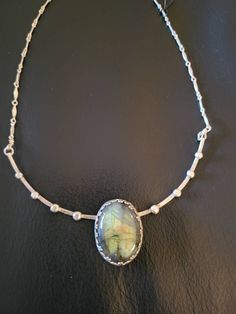 1"×3/4" labradorite oval is set in patterned oval and placed on a curved sterling bar with dots. A neck ring/ chain combination! Blue and golden labradorite shines from within when it hits the light. A very beautiful addition to your neck accessories! Bar length is 5" and necklace can be worn 16-19" long. Oval Labradorite Jewelry Stamped 925, Oval Labradorite Necklace With Large Stone, Oval Labradorite Cabochon Necklace, Oval Labradorite Silver Necklace, Silver Oval Labradorite Necklace, Silver Labradorite Oval Necklace, Unique Oval Labradorite Necklace, Neck Ring, Curved Bar