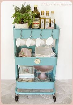 a blue cart with pots and pans on it, sitting in front of a wall