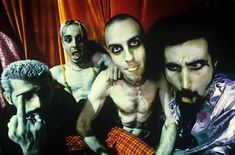 three men with makeup on their faces and one man in costume posing for the camera