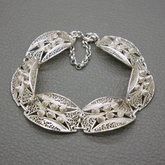 A lovely vintage sterling silver filigree bracelet. This panel bracelet was hand made circa 1970's in traditional Javanese yogya (djokja) filigree technique. The bracelet will be shipped in a gift box. Bracelet length: about 7 Inches (18.0 cm) - the bracelet is made to fit a medium wrist. Bracelet width 2/3 Inches (1.65 cm)  Weight: 14.1 grams The bracelet was professionally tested for high grade (sterling) silver The bracelet is closing securely with a spring ring clasp. There is also an extra Filigree Bracelet, Wrist Bracelet, Coral Jewelry, Sterling Silver Filigree, Bracelet Vintage, Silver Filigree, Chain Link Bracelet, Spring Rings, Sterling Silber