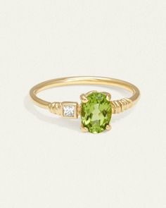 a gold ring with an oval green stone and two small white diamonds on the side