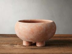 a large pink bowl sitting on top of a wooden table next to a gray wall