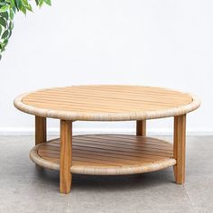 a wooden table sitting on top of a cement floor next to a potted plant