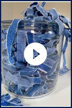 a glass jar filled with blue ribbon on top of a table