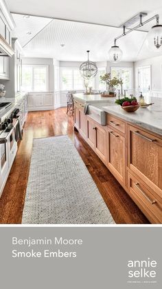 a large kitchen with wooden cabinets and white counter tops, along with an area rug that matches the hardwood flooring