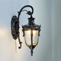 an old fashioned wall light hanging on the side of a white wall with two lights