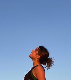 a woman is flying a kite in the sky with her head tilted to the side