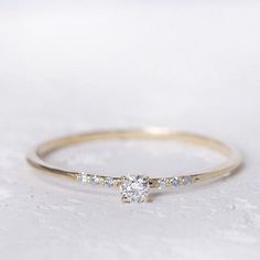 a yellow gold ring with three stones on it and a diamond in the middle, sitting on a white surface