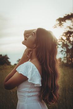 a woman with long hair standing in a field