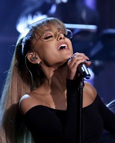 a woman with glasses on singing into a microphone