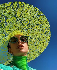 a woman wearing sunglasses and a green hat with lacy doily on it's head