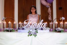 a woman standing in front of a table with candles on it and a name sign