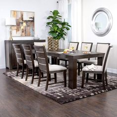 a dining room table with chairs and a potted plant in the middle of it