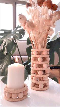 a vase filled with lots of white flowers next to a lit candle on top of a table