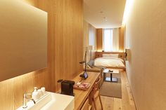 a room with a bed, desk and sink in it next to a wooden wall