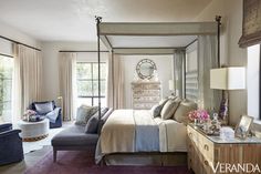 a bedroom with a canopy bed and purple carpeted flooring in front of windows