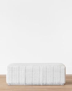 a white mattress sitting on top of a wooden floor in front of a white wall