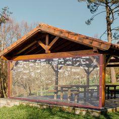 a covered picnic area in the middle of a park with trees and grass around it