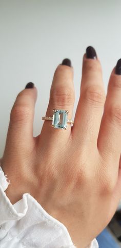 a woman's hand wearing a ring with an aqua blue topazte stone