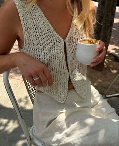 a woman sitting in a chair holding a cup of coffee