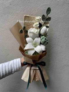 a bouquet of flowers is wrapped in brown paper and tied to the wall with ribbon