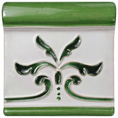 a green and white tile with an ornate design on the bottom, in front of a white background