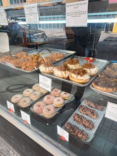 donuts and other pastries are on display in a bakery's glass window