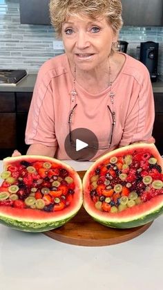 a woman sitting at a table with two slices of watermelon