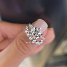 a woman's hand holding an engagement ring with diamonds on the top and bottom