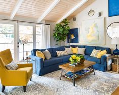 a living room with blue couches and yellow chairs