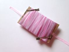 a pink piece of fabric with some scissors in it on a white surface and two strings attached to the end