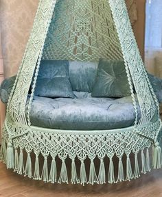 a blue couch sitting inside of a green netted hammock with tassels