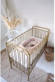 a gold metal crib with a blanket in the middle and a rug on the floor next to it