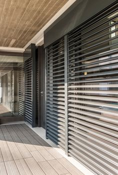 an outdoor area with wooden flooring and louvered metal slats on the walls