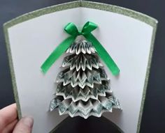 someone is holding up a folded christmas tree card