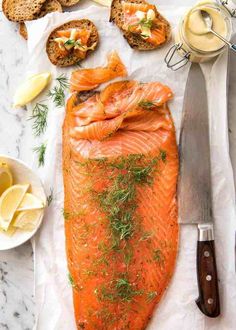 salmon and bread on a table with butter, dill, lemon wedges and sauce