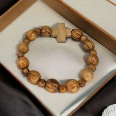 "Handcrafted in the Holy Land, our Olive Wood Bracelet is a truly unique piece of jewelry. Made from high-quality olive wood, this bracelet features a cross pendant adorned with olive wood bead.  -The word \"Jerusalem\" is engraved on one side. -Versatile and suitable for both men and women, this bracelet makes for a meaningful gift for any age. - With its natural beauty and spiritual significance, wearing this Olive Wood Bracelet is like carrying a piece of the Holy Land with you wherever you g Wooden Bracelets With Round Beads For Gifts, Wooden Beaded Bracelets For Gifts, Natural Wood Beaded Bracelets As Gift, Brown Wooden Beaded Bracelet As A Gift, Natural Wood Beaded Bracelet As Gift, Natural Wood Beaded Bracelets For Gifts, Natural Wood Round Beads Bracelet Gift, Gift Natural Wood Round Bead Bracelets, Brown Wooden Beaded Bracelets As A Gift