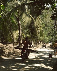 a man riding a motorcycle down a dirt road with a surfboard strapped to his back