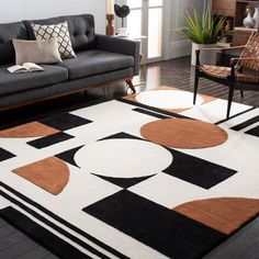 a modern living room with black, brown and white rugs on the hardwood floor