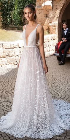 a woman in a white wedding dress standing on a cobblestone walkway with her back to the camera