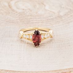 a gold ring with an oval cut garnetia stone surrounded by small white diamonds