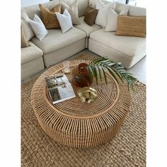 a wicker coffee table sitting on top of a rug in front of a couch