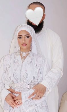 a man and woman dressed in white are posing for the camera with a heart on their forehead