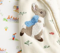 a baby's sweater with an embroidered rabbit on the front, and a wallpapered background